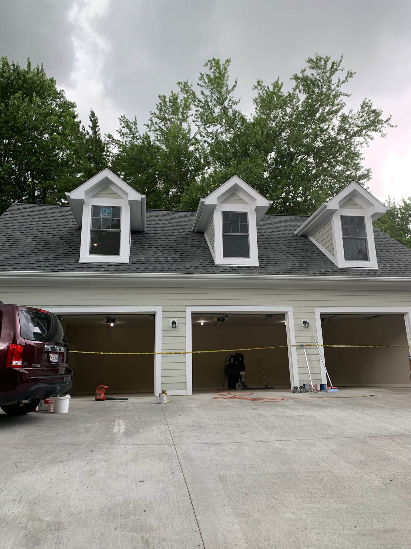 A car is parked in front of a house with three garage doors.