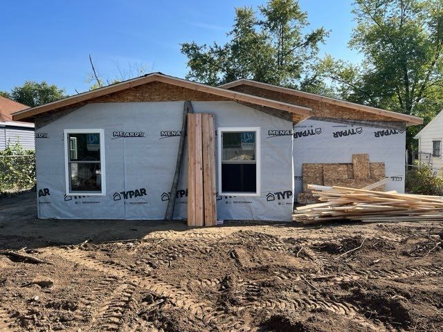 A small house is being built in a dirt field.