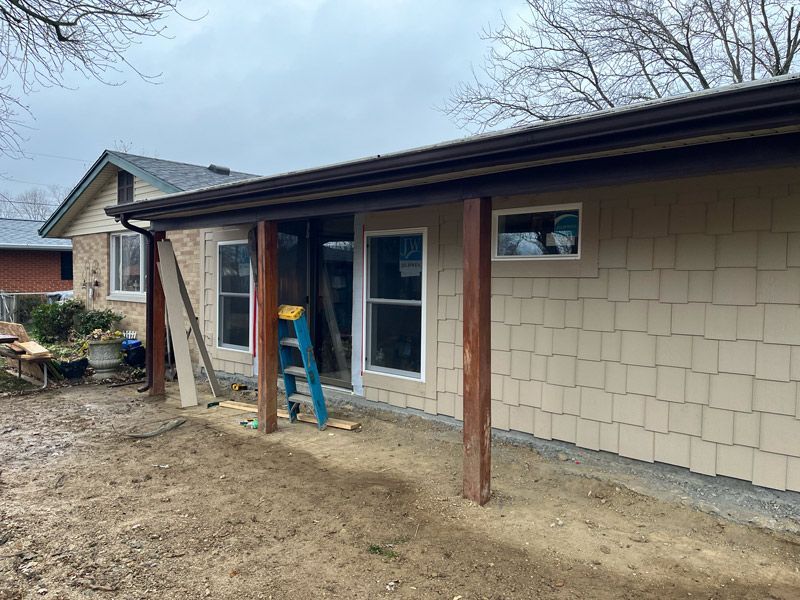 A house with a porch and a ladder in front of it.