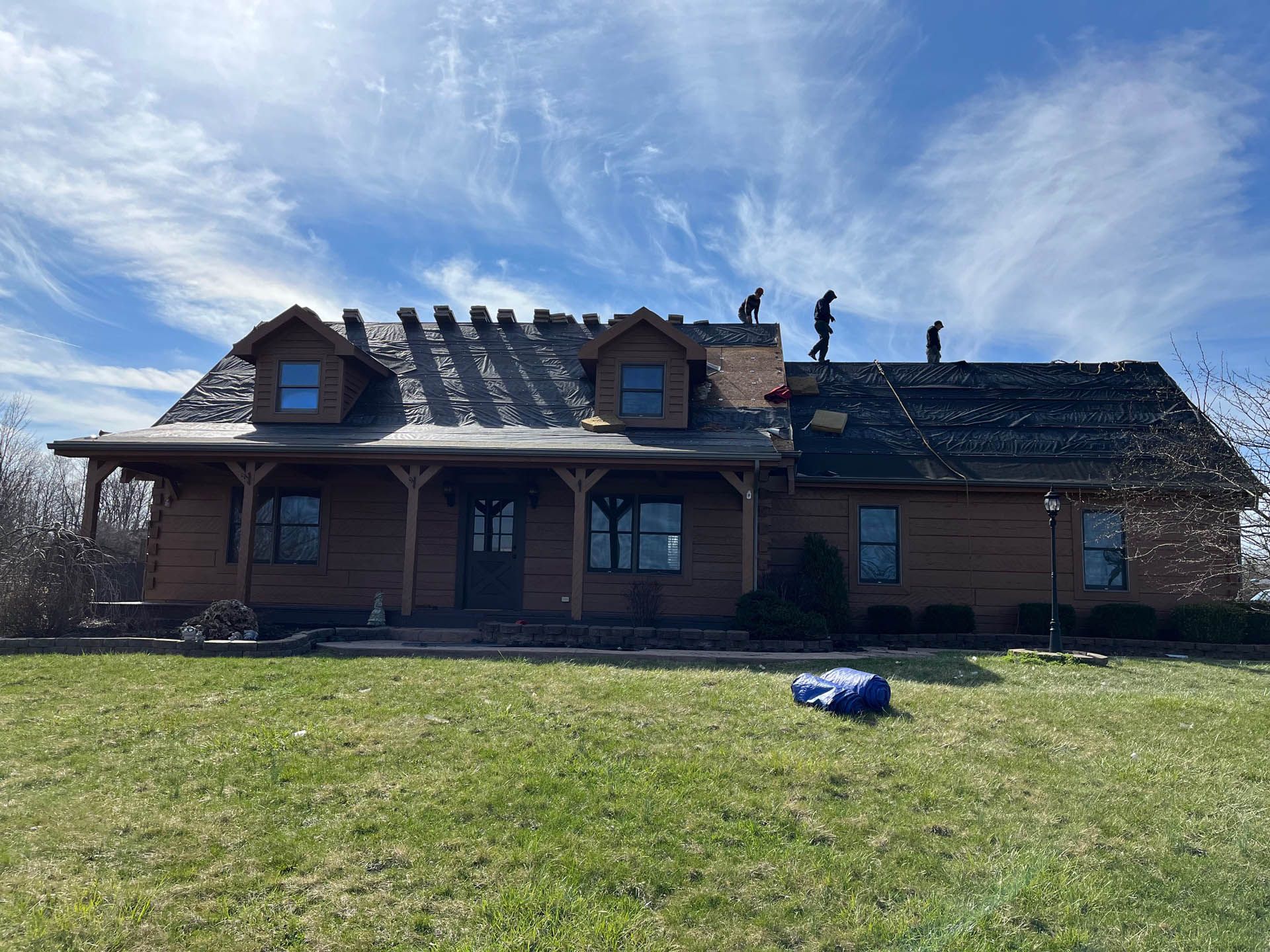 A large wooden house is being remodeled with a new roof.