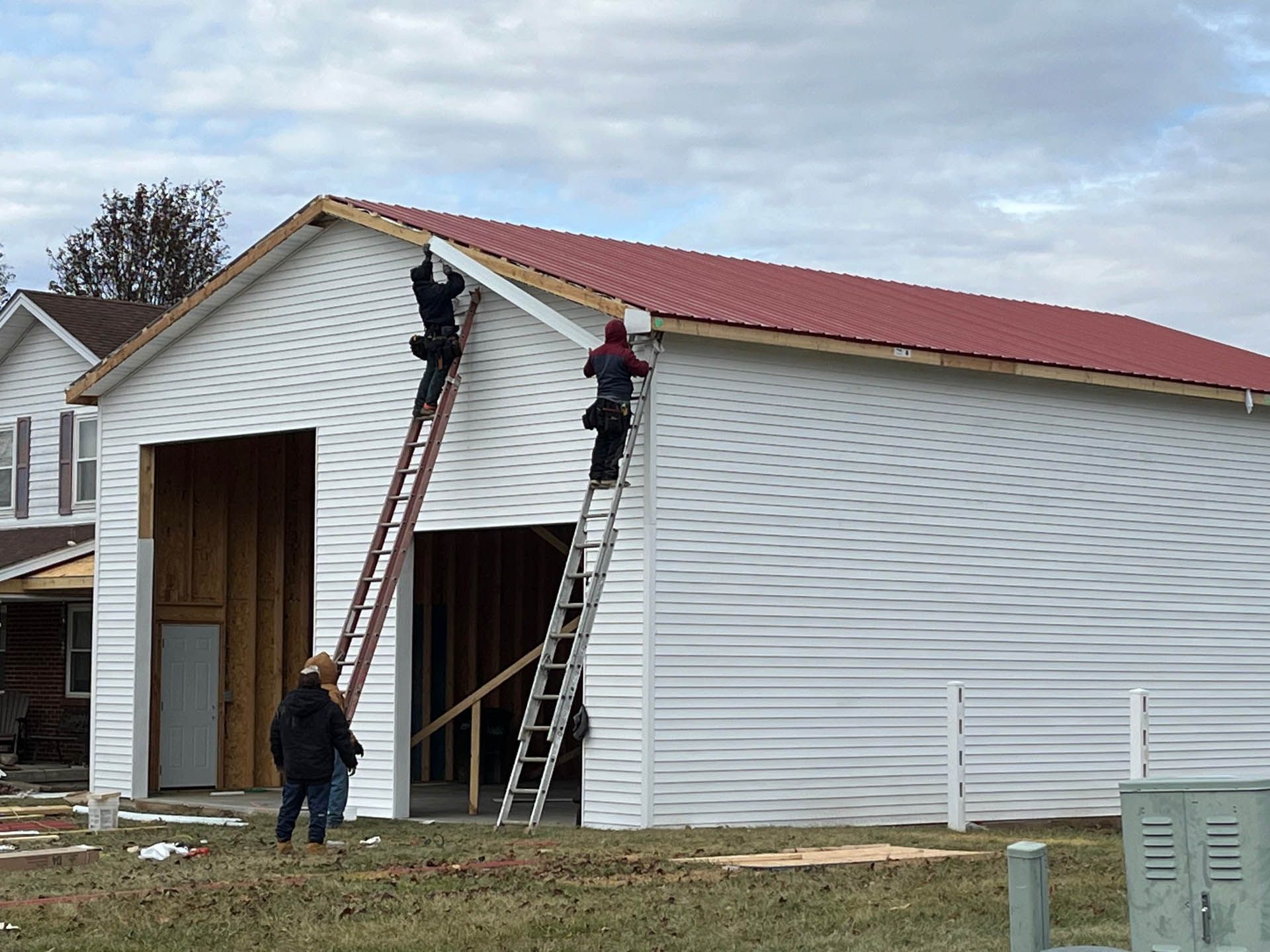 A group of people are working on a white building with a red roof.