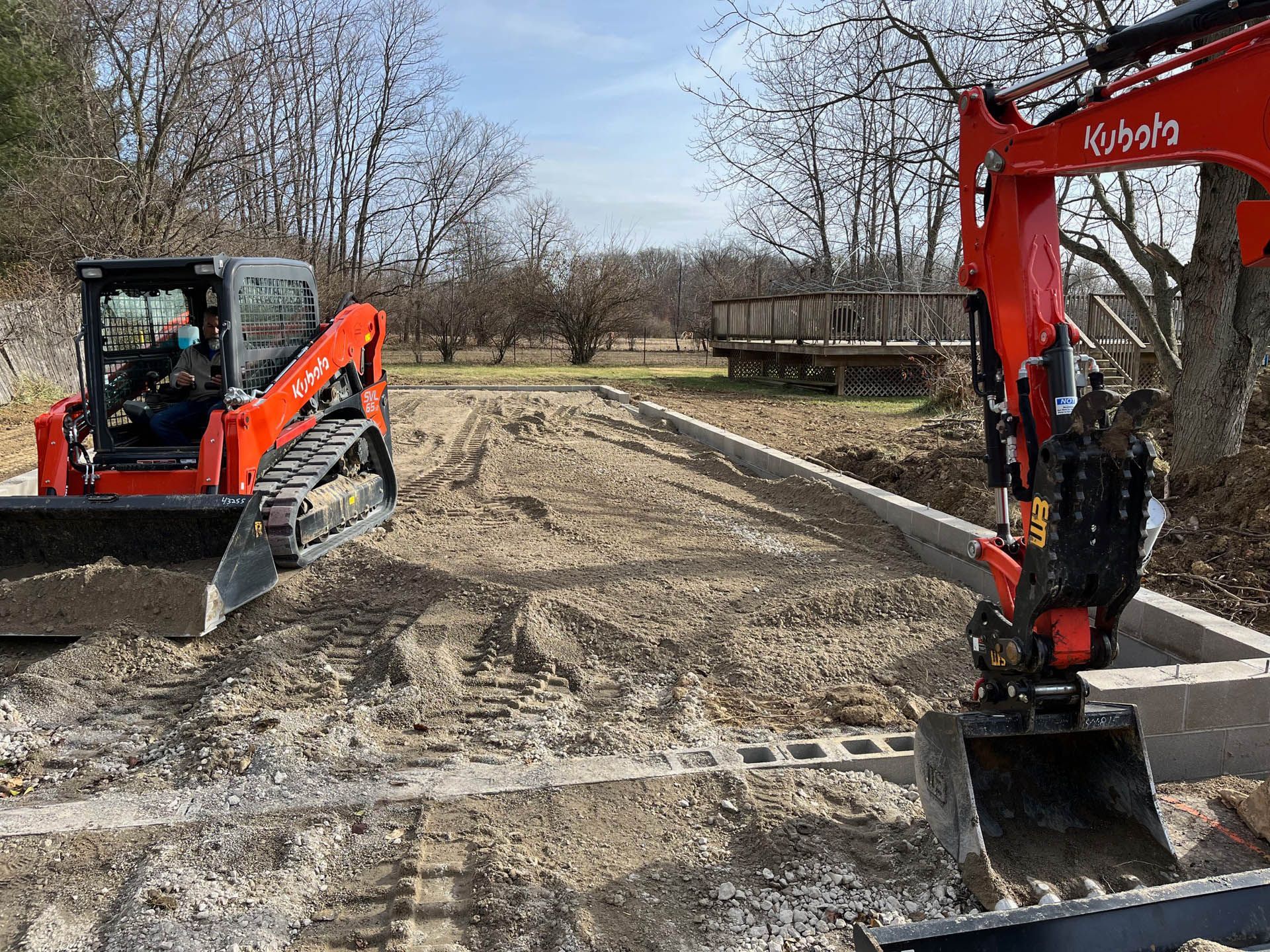 A bulldozer and an excavator are working on a dirt road.