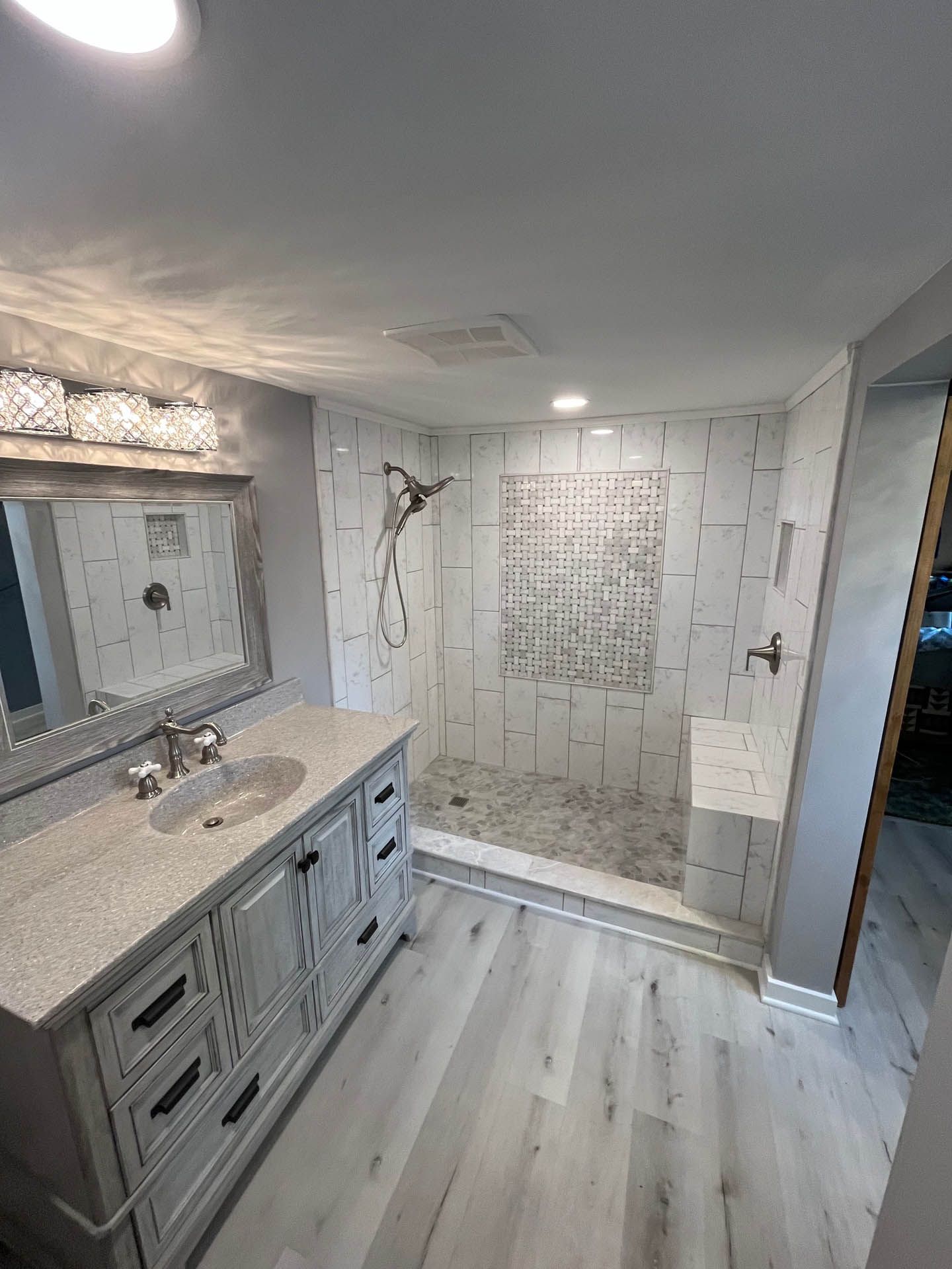 A bathroom with a sink , mirror , and walk in shower.