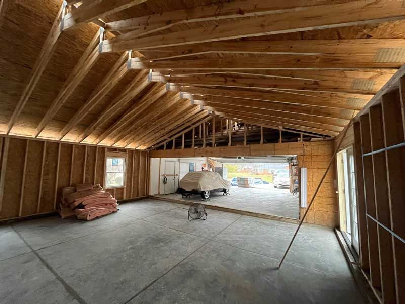 A room with a wooden ceiling and a car in the background.