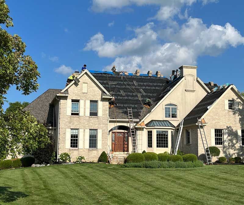 A large brick house with a roof being installed.
