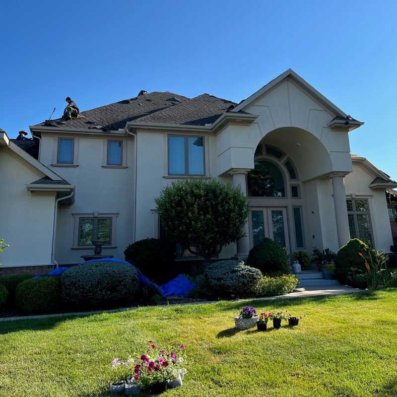 A large white house with a man on the roof.
