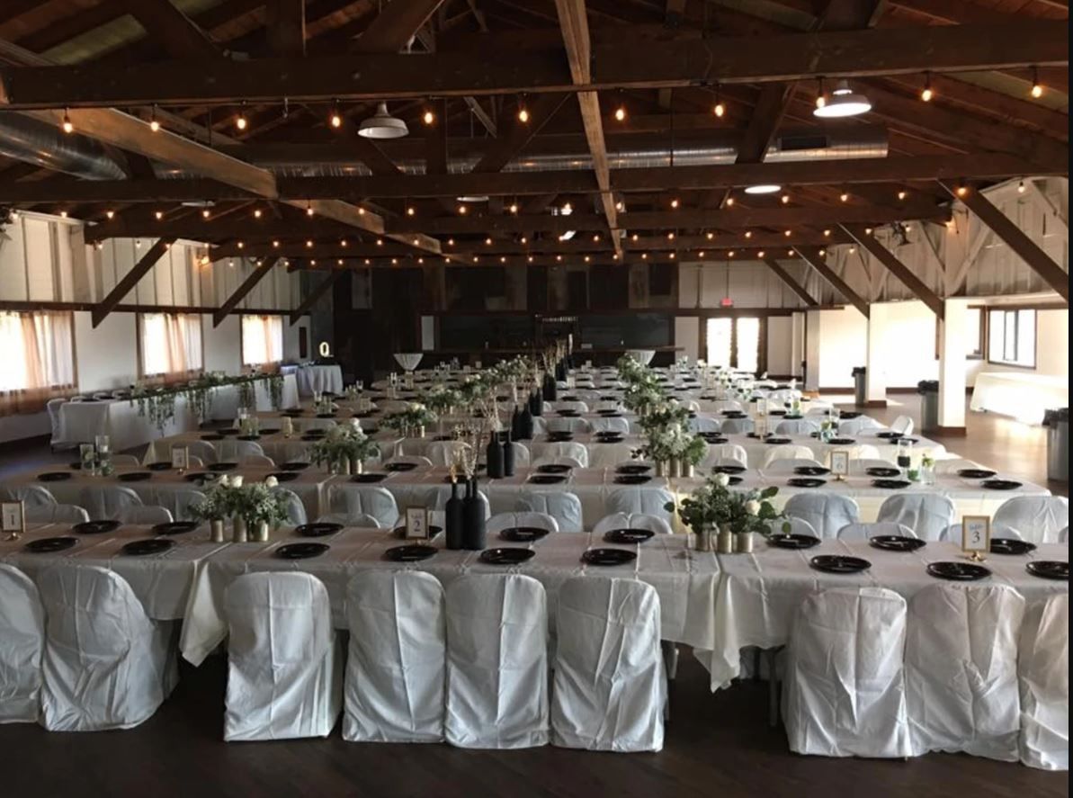 A large room with tables and chairs set up for a wedding