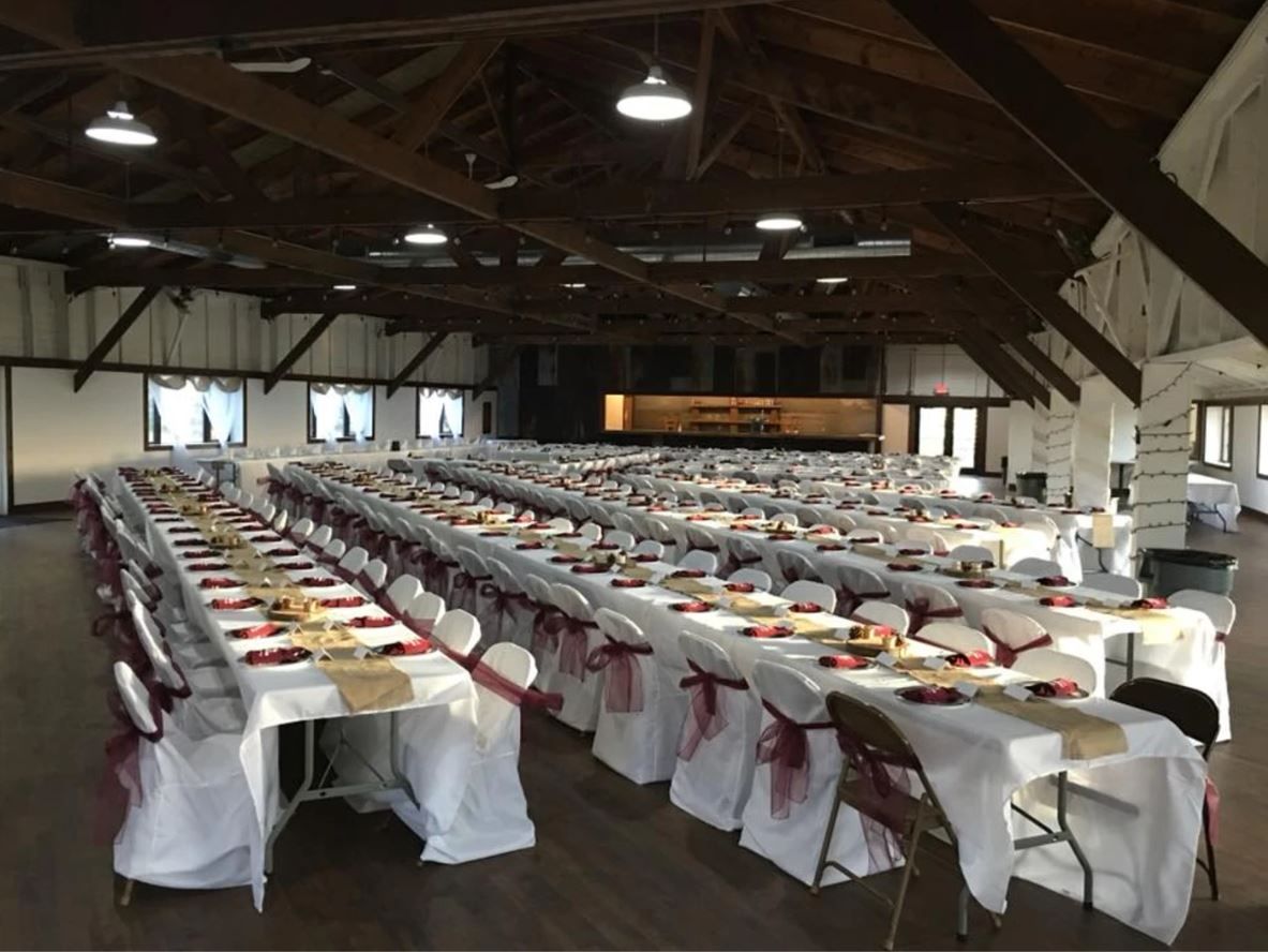 A large room with tables and chairs set up for a wedding reception