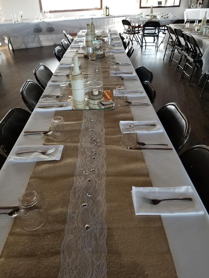 A long table with a table runner and utensils on it.