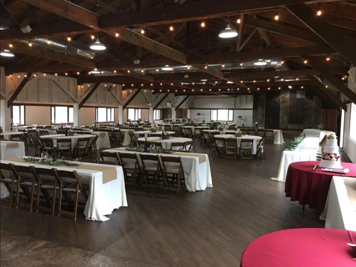 A large room with tables and chairs for a wedding reception