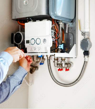 Person working on a wall-mounted boiler, tightening a fitting with a tool.