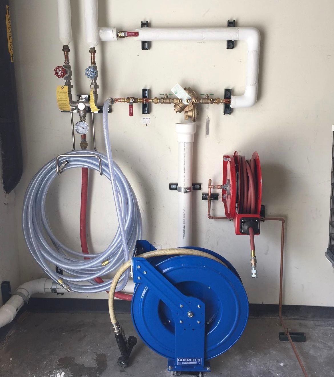 A blue hose reel is in a room with pipes