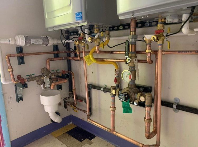 A room with a lot of pipes and appliances on the wall.