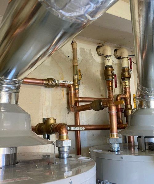 Two water heaters with copper pipes coming out of them