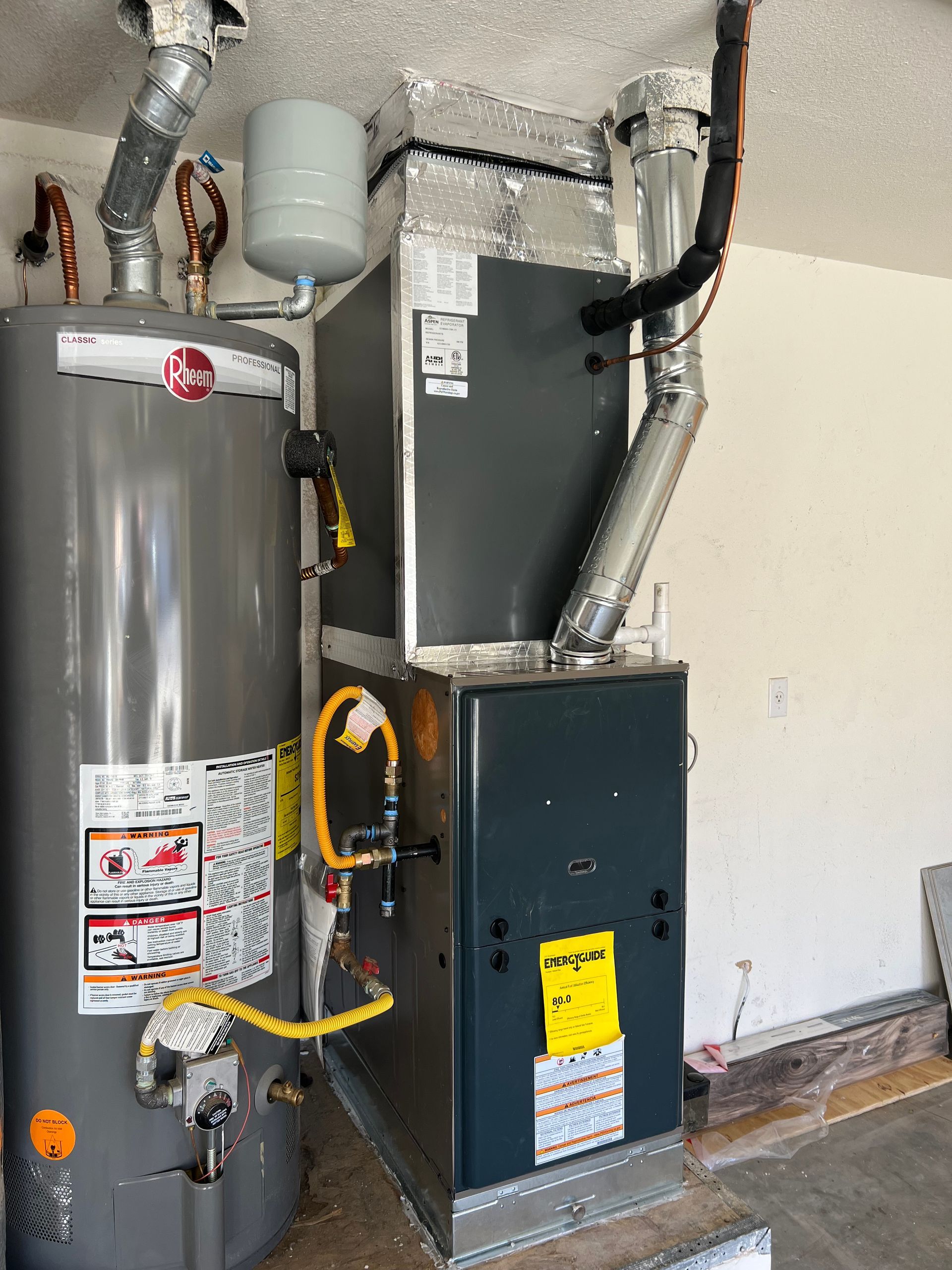 A water heater and an air conditioner are in a garage.