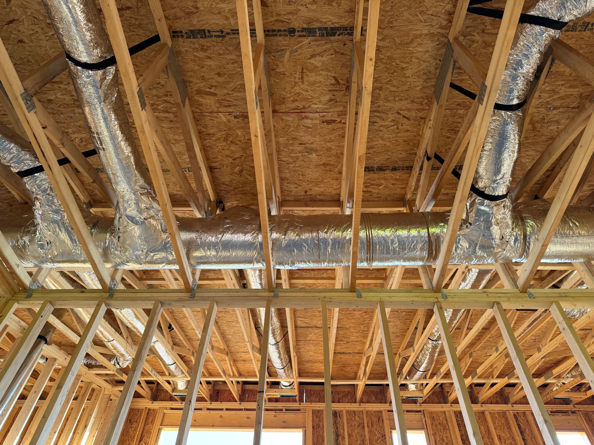 The ceiling of a house under construction with a lot of pipes coming out of it.
