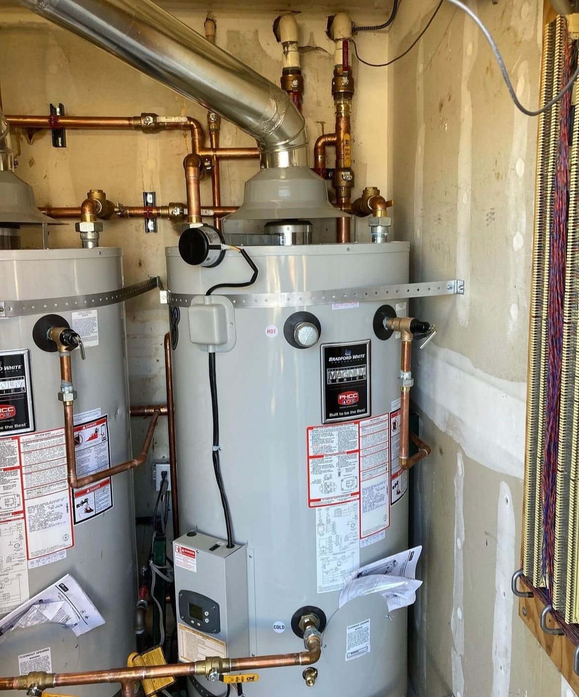 Two water heaters are sitting in a room next to each other.