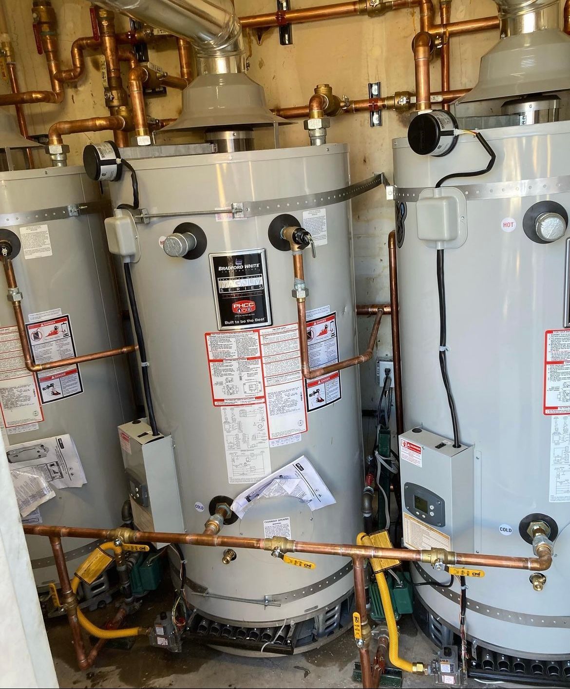 Three water heaters are sitting next to each other in a room.