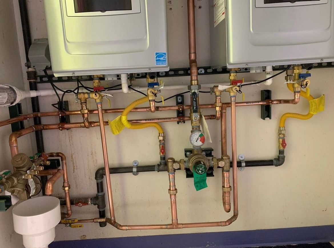 A bathroom with two washers and dryers and copper pipes.