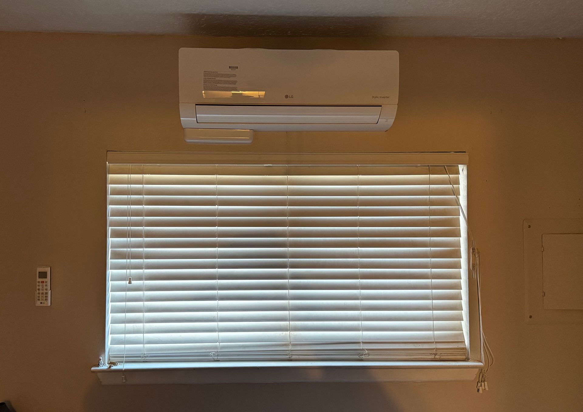A window with blinds and an air conditioner above it