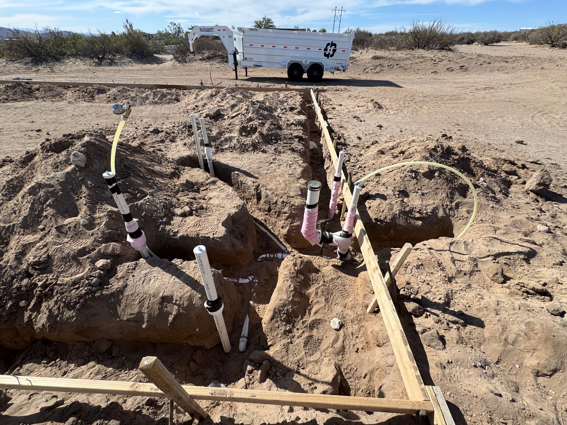 A white truck is parked in the middle of a dirt field.