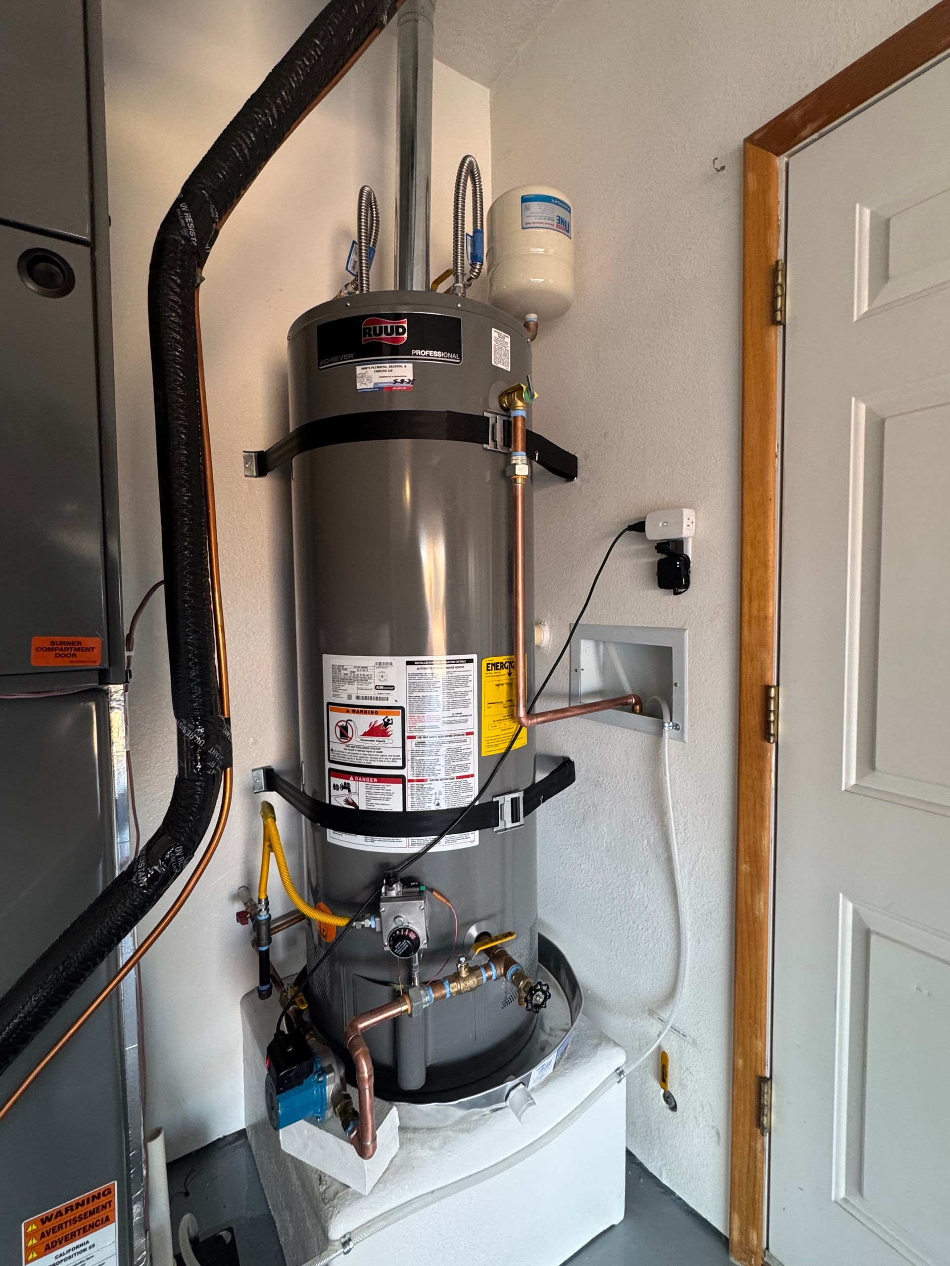 A water heater is sitting on top of a washer and dryer in a room.