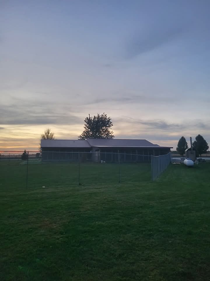 Building silhouetted against a cloudy sky at dusk. Green lawn in foreground.