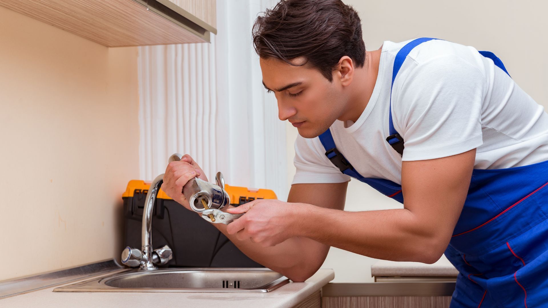 A man and a woman are working on a kitchen sink.