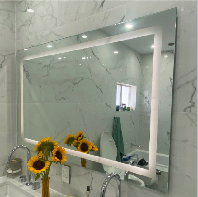 Bathroom mirror with illuminated frame, reflecting sunflowers, sink, and marble wall.