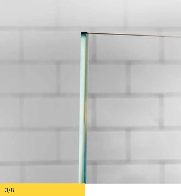 Clear glass shower panel edge against a white brick wall.