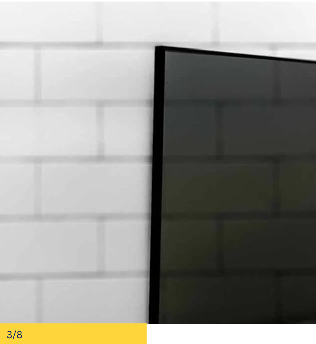 Black television screen mounted on a white brick wall.