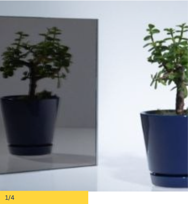 A bonsai tree in a blue pot is reflected in a grey mirror. The tree is on a white background.