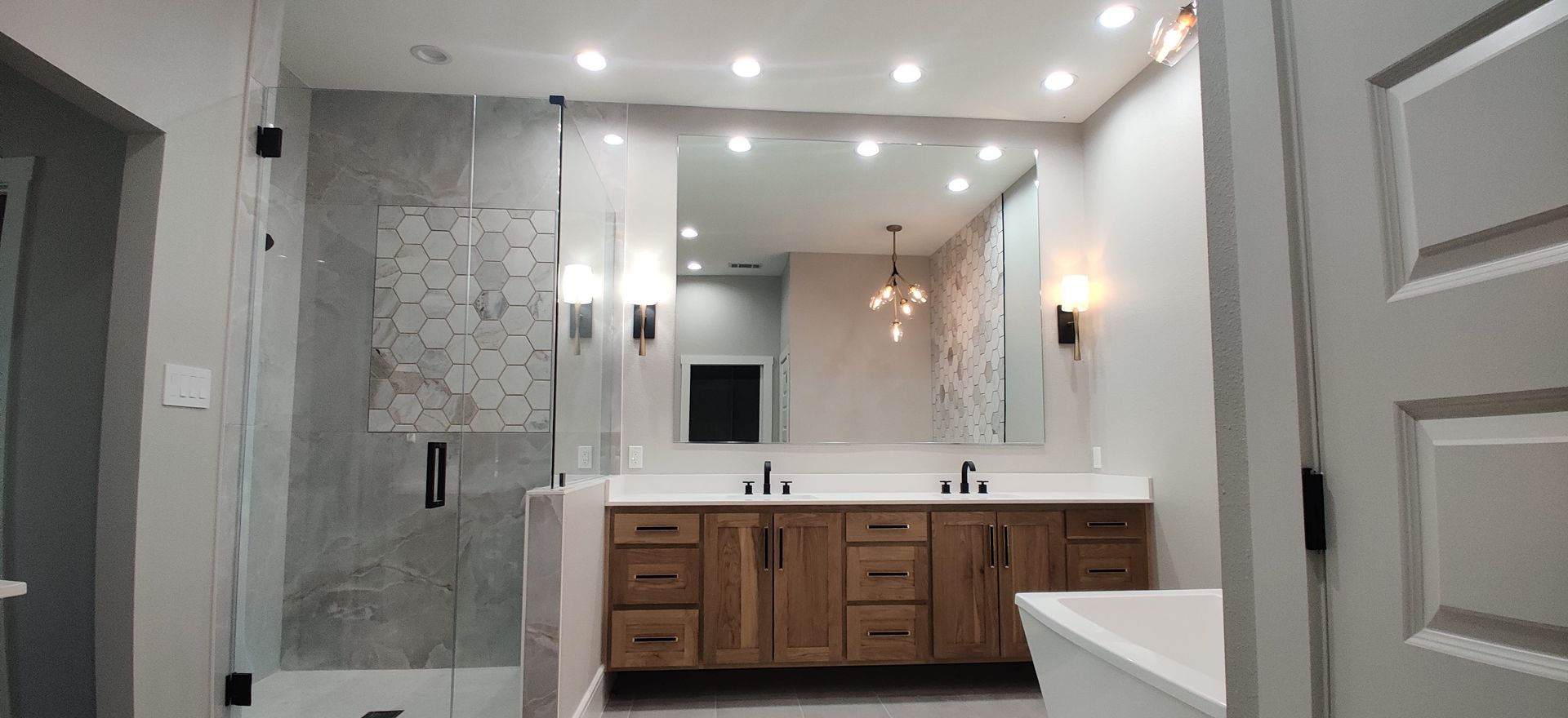Framless polished edge mirror in a modern bathrom with modern lighting and updated cabinetry