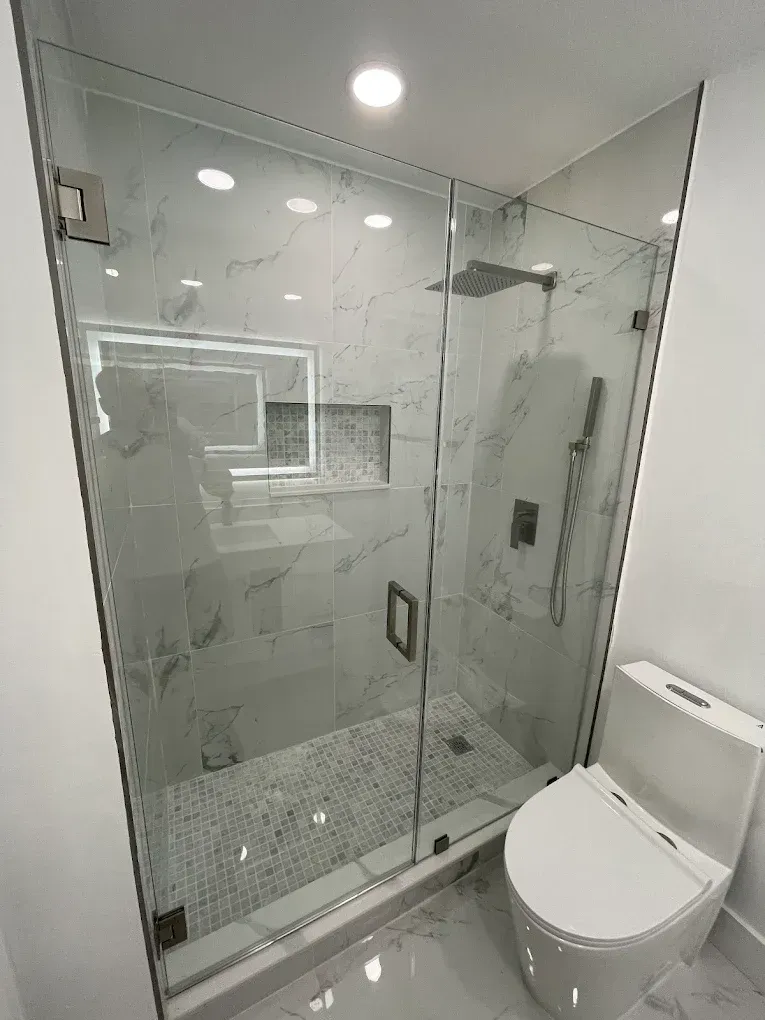 Puerta y panel fijo de vidrio instalada en una ducha de esquina en Westchester.