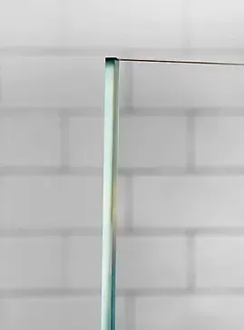 Clear glass shower door corner against white brick.