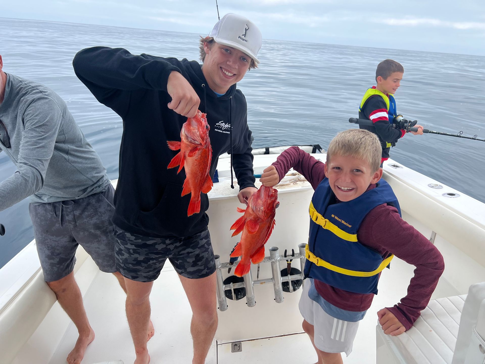 Two boys are holding fish on a boat in the ocean.