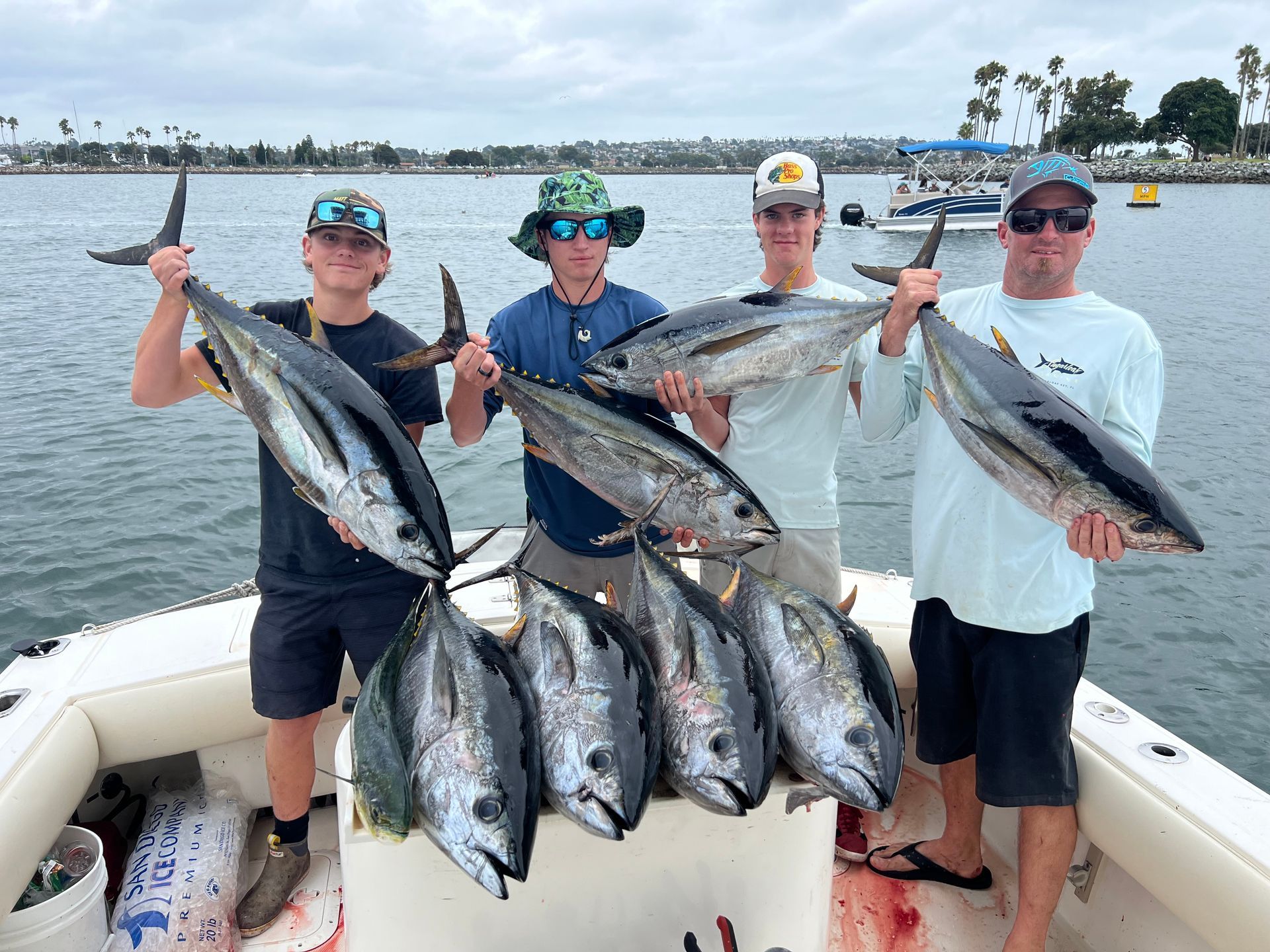 A group of men are standing on a boat holding fish.