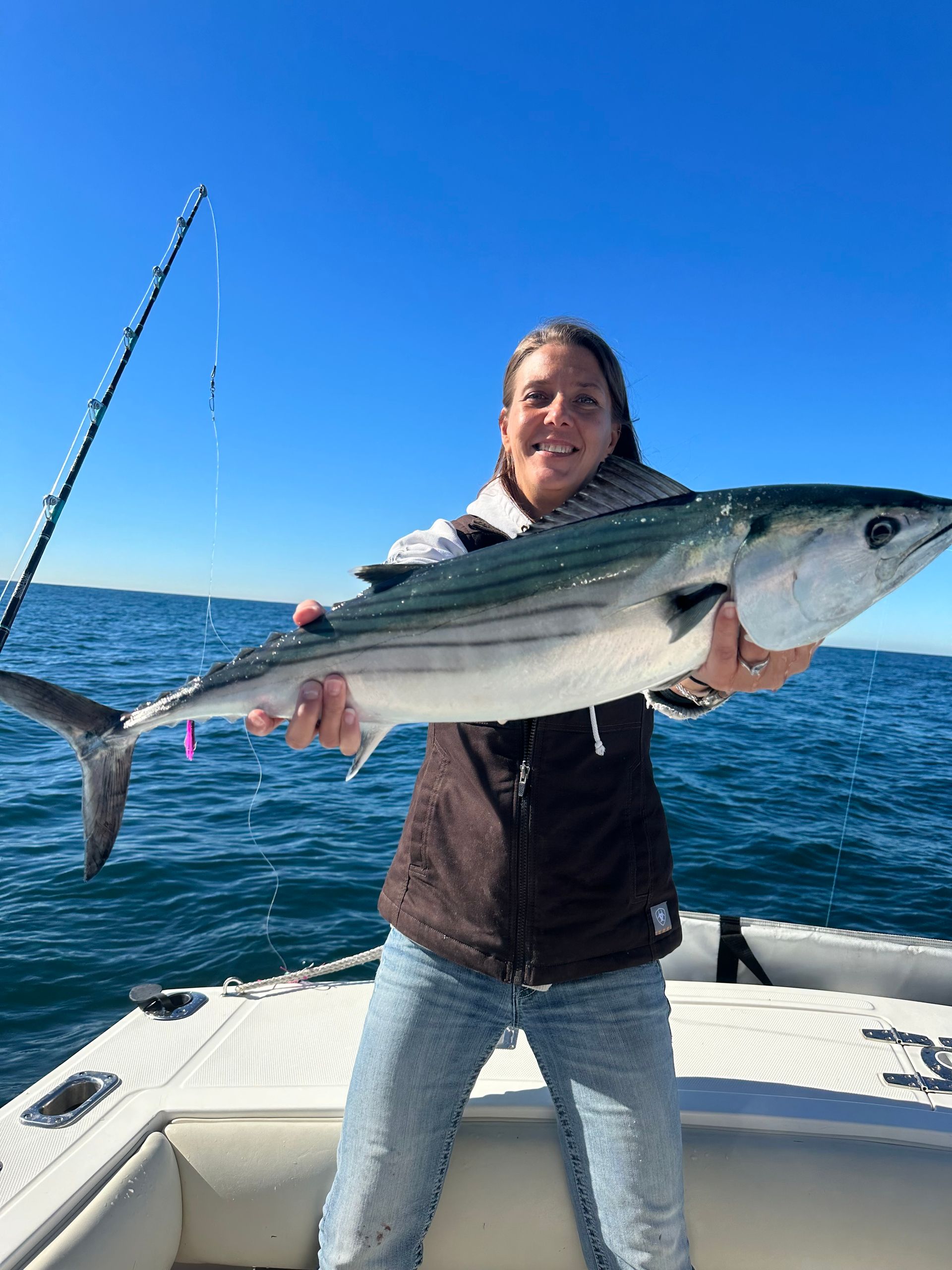 A woman is holding a large fish on a boat.