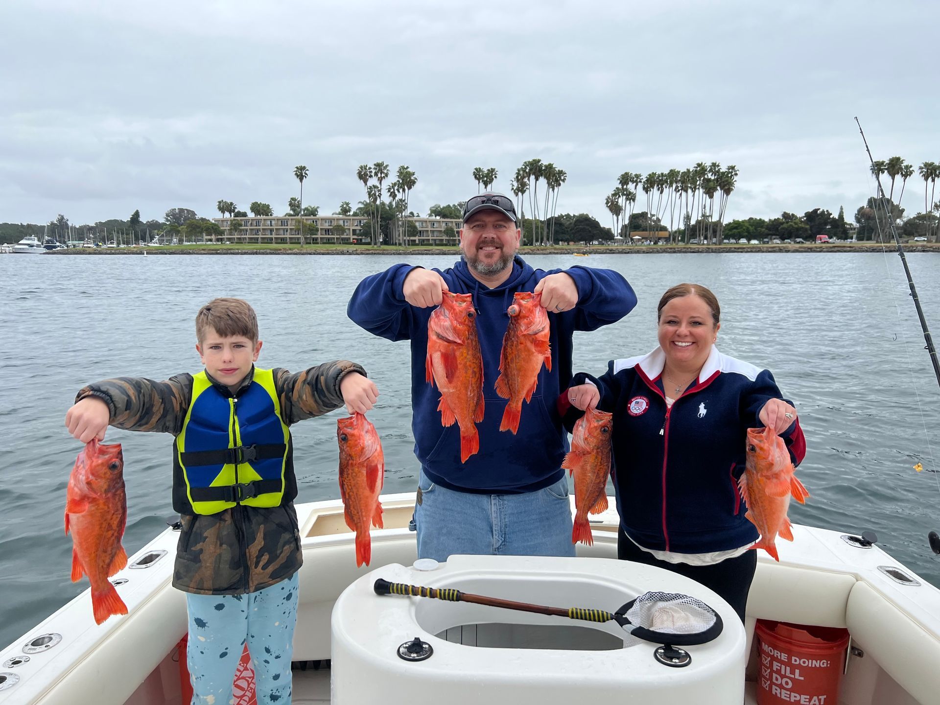 A man , woman and child are holding fish on a boat.
