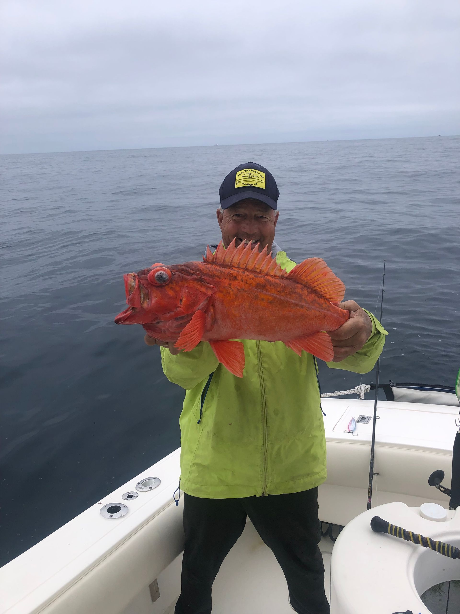 A man is holding a large fish on a boat in the ocean.