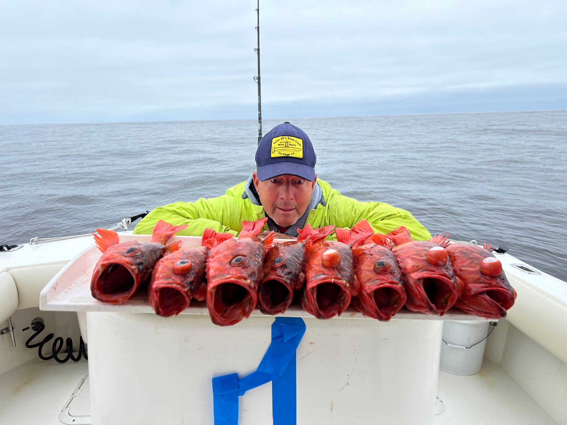 A man is standing on a boat holding a tray of fish.