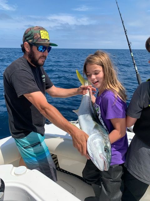 A man and a girl holding a fish on a boat