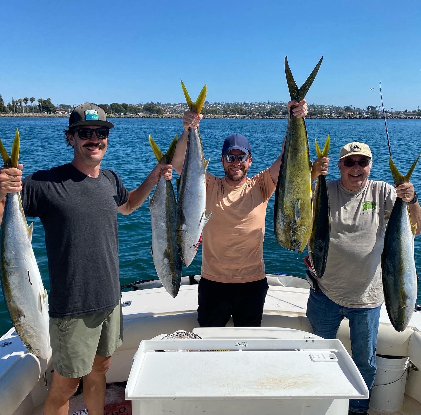 Three men are holding fish in their hands on a boat