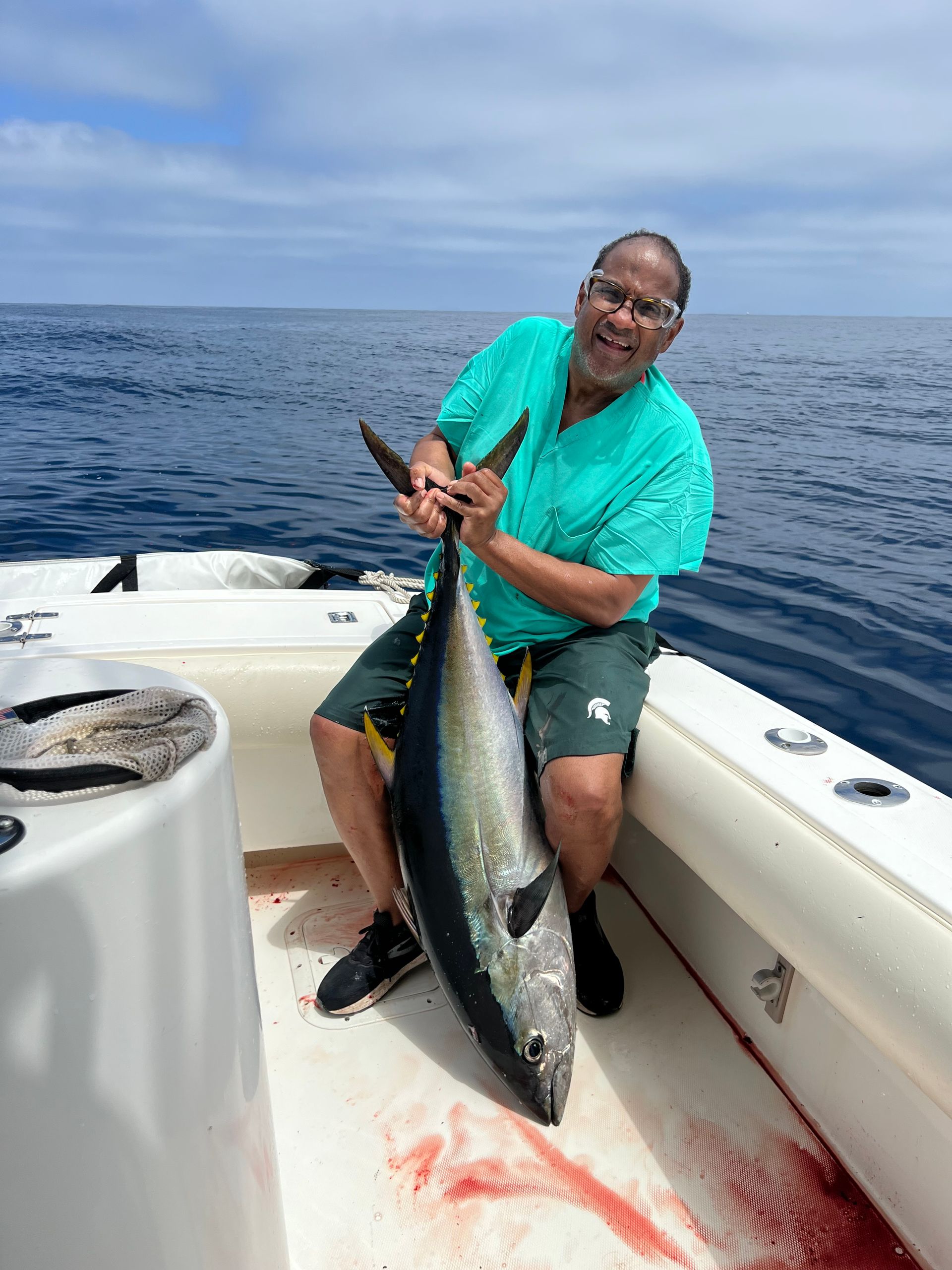 A man is sitting on a boat holding a large fish.