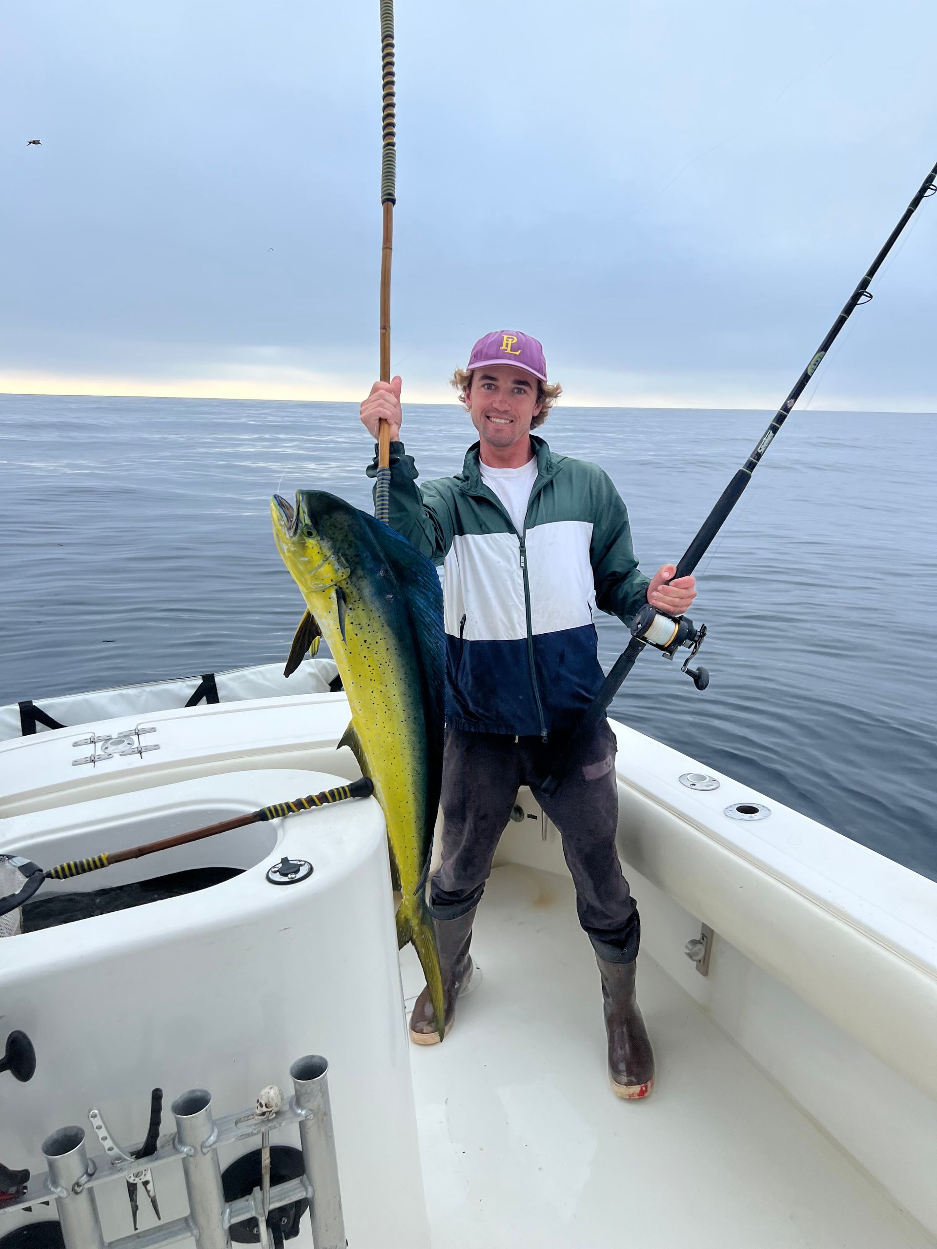 A man is standing on a boat holding a large fish.