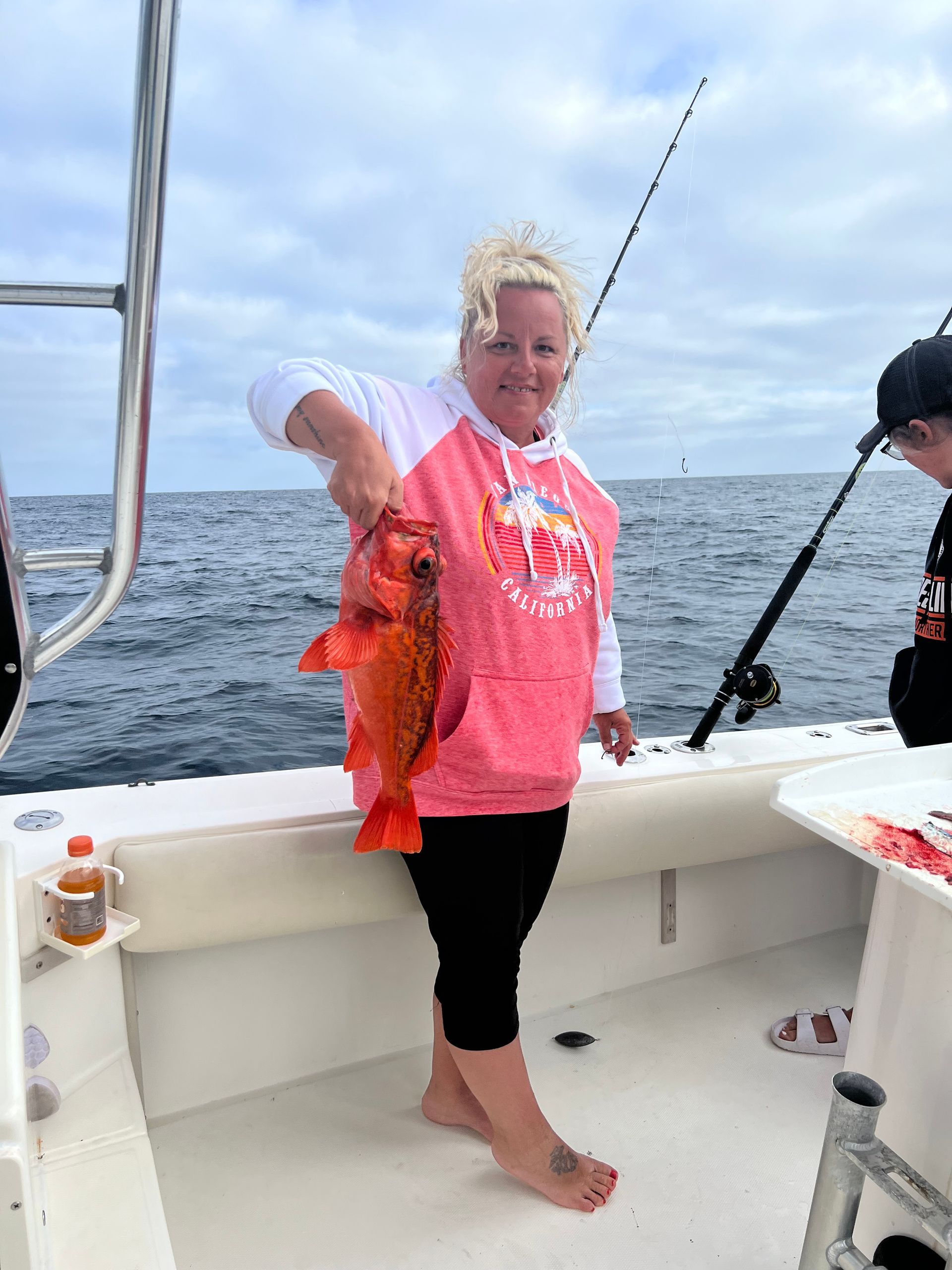 A woman is standing on a boat holding a fish.
