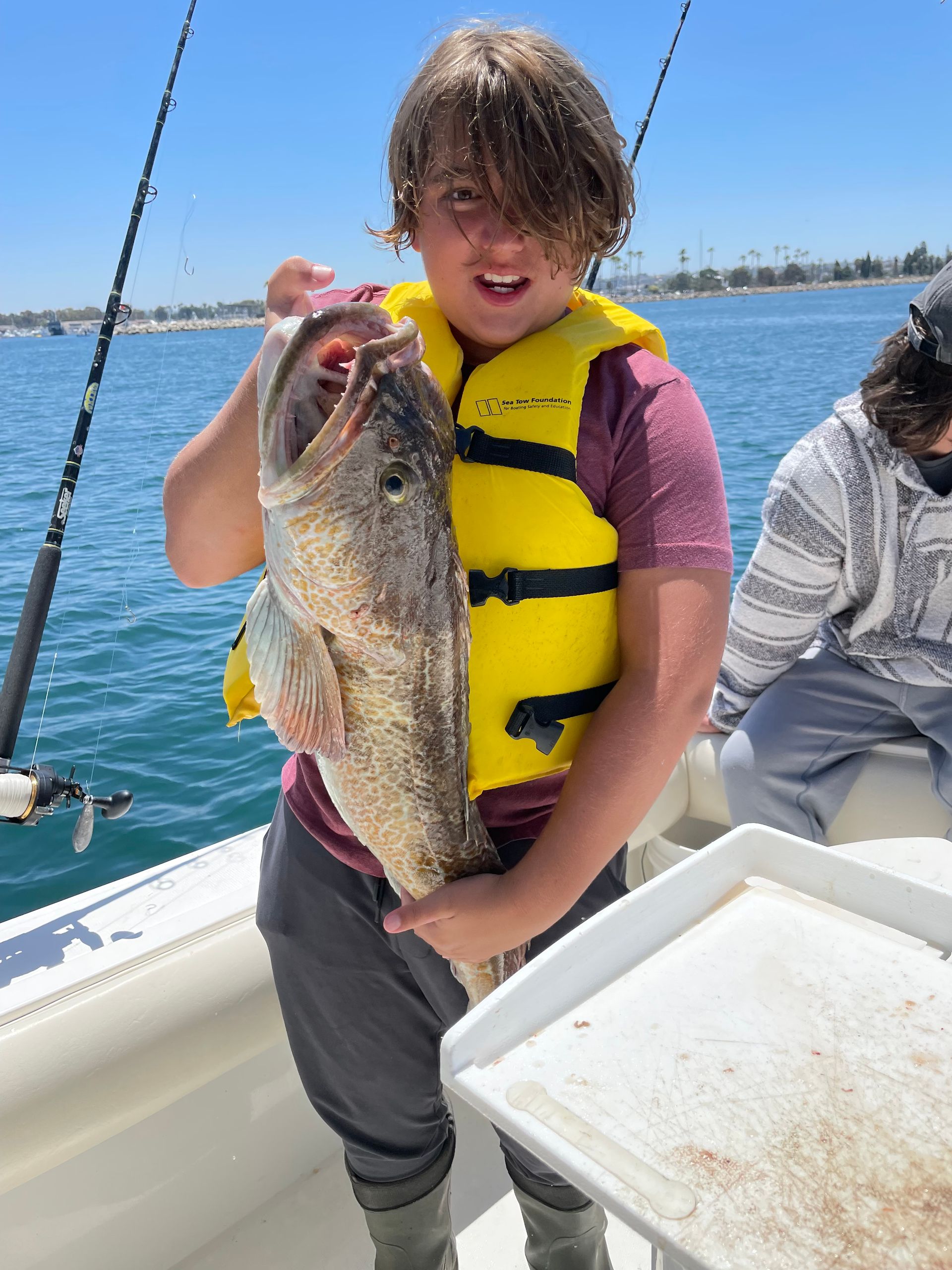 A young boy is holding a large fish on a boat