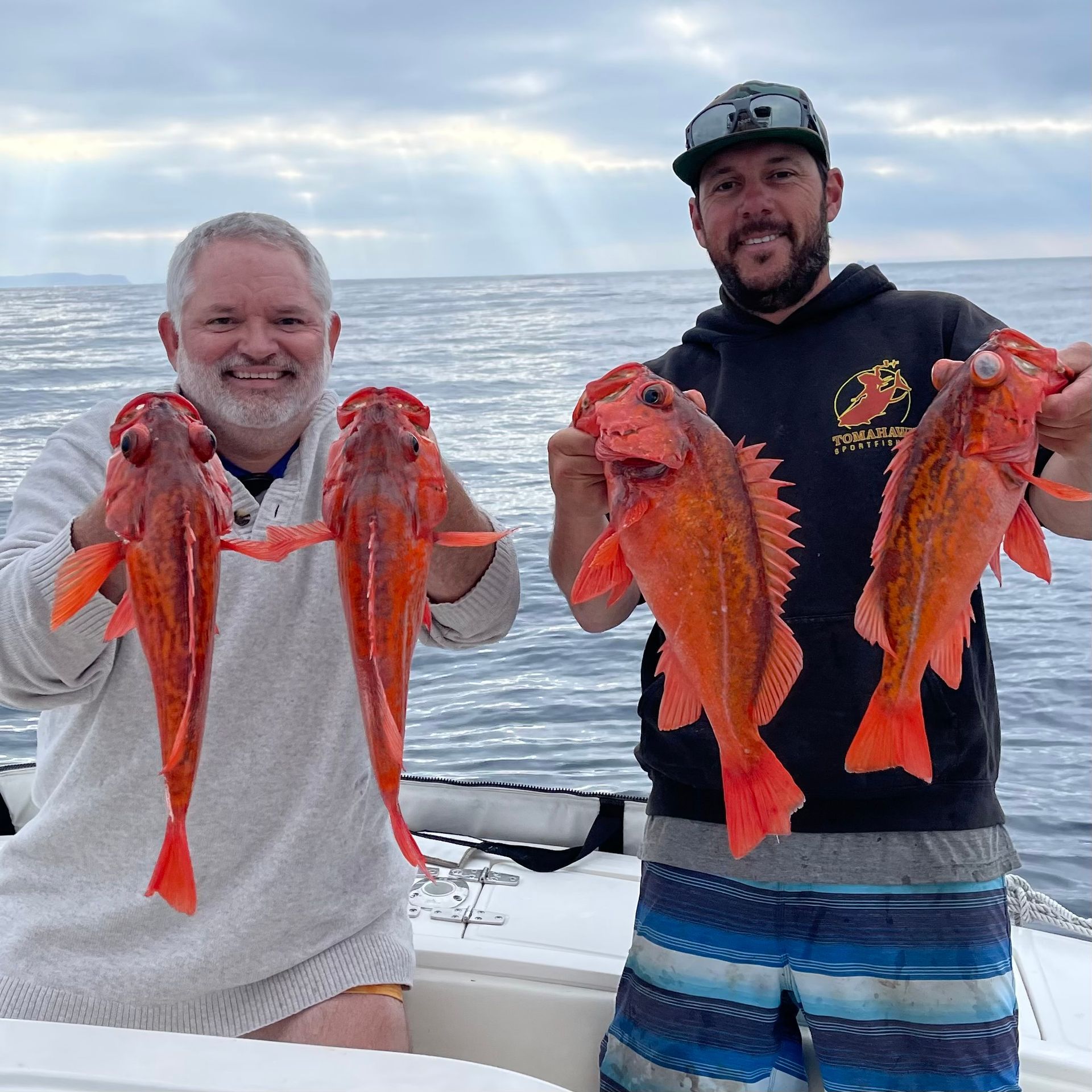 Two men are holding fish in their hands on a boat