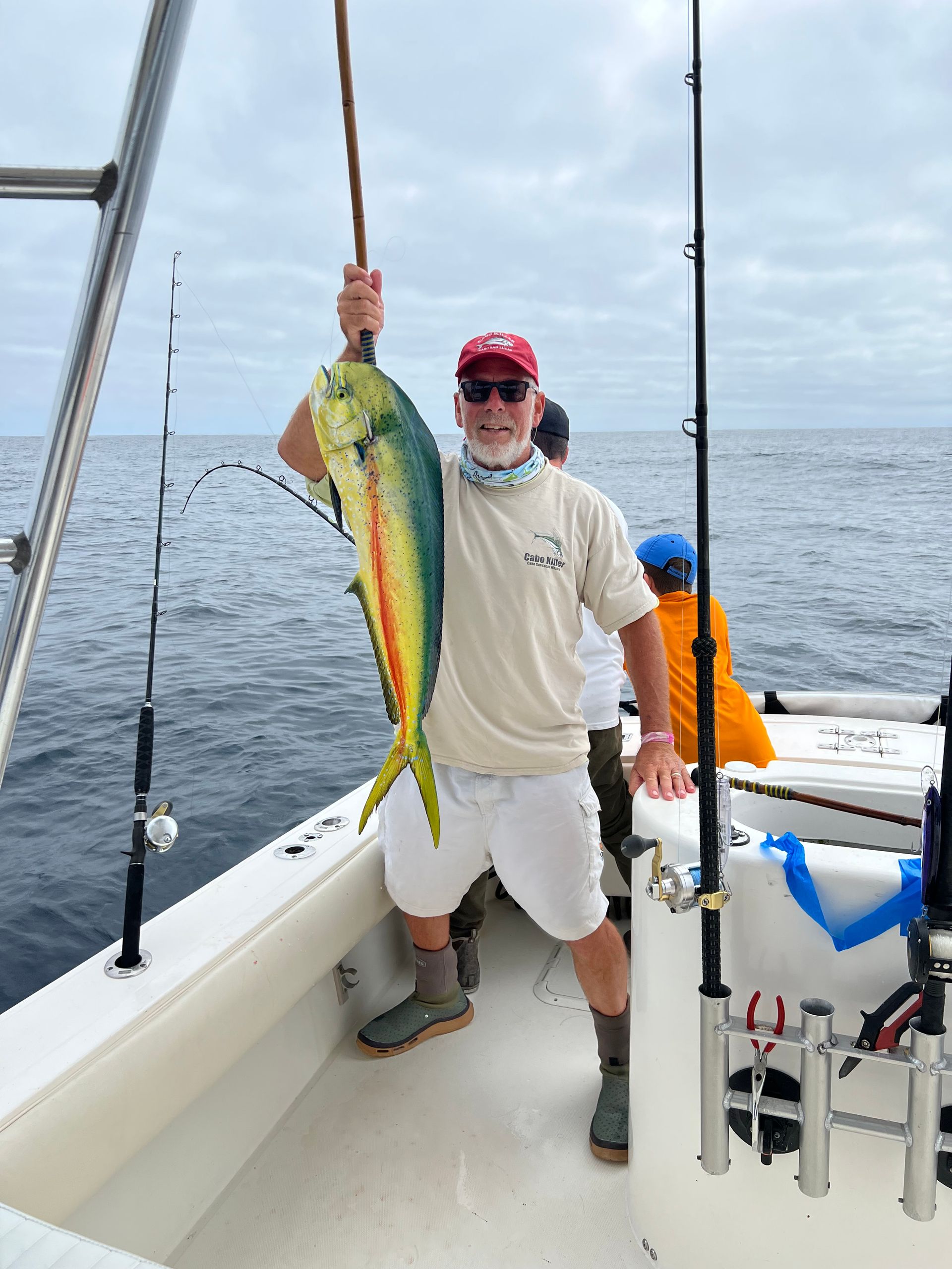 A man is holding a fish on a boat in the ocean.