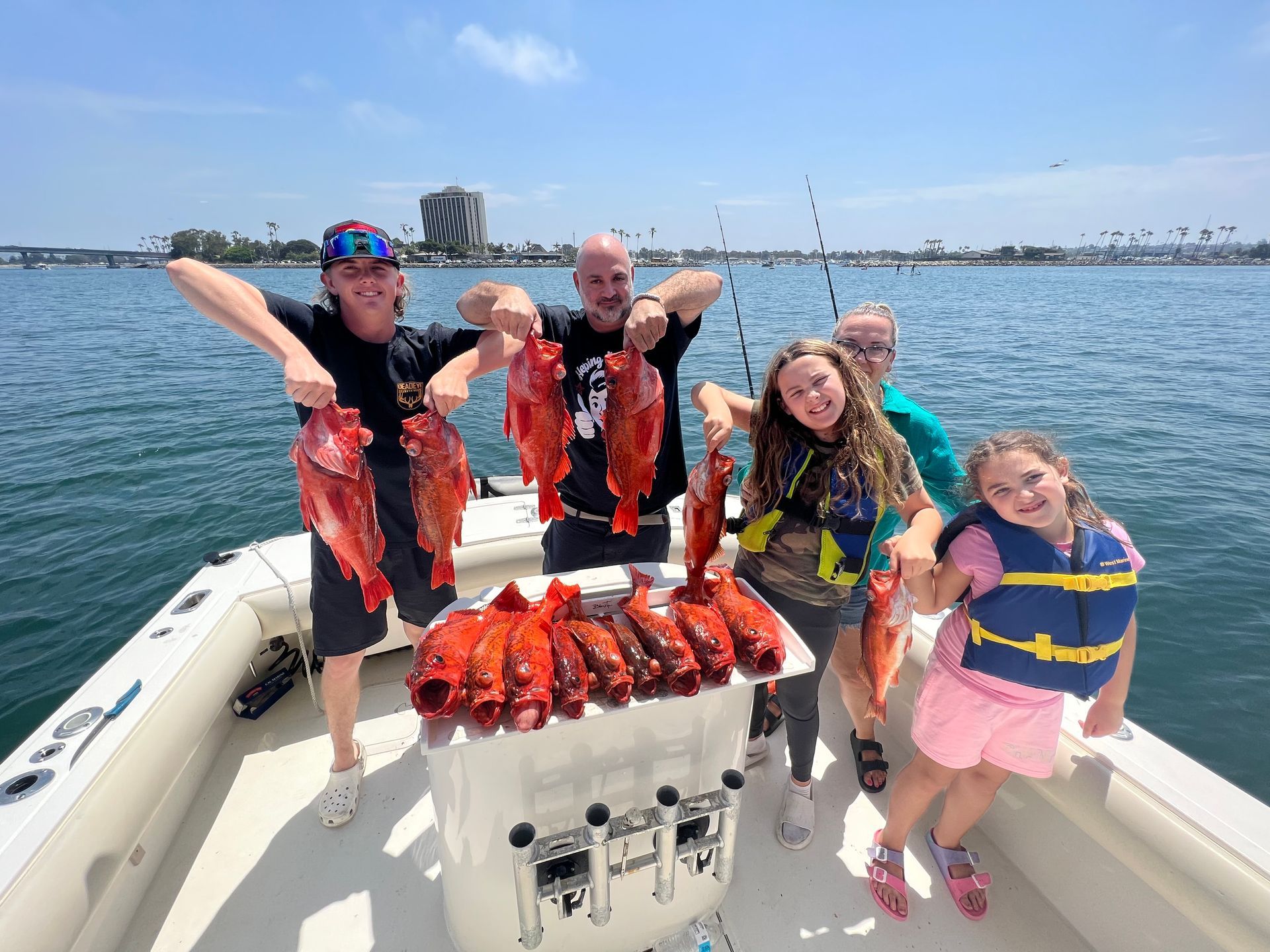 A group of people are standing on a boat holding fish.